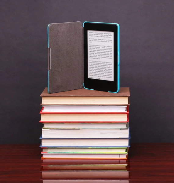 Lector de libros electrónicos y apilar libros antiguos en la mesa de escritorio de madera —  Fotos de Stock