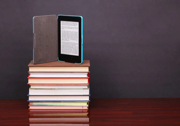 Elektroniczne książki czytelnik i stos starych książek na stole drewniane biurko — Zdjęcie stockowe