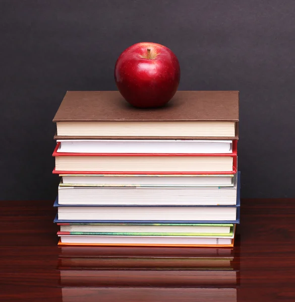 Manzana con libros sobre mesa de madera — Foto de Stock