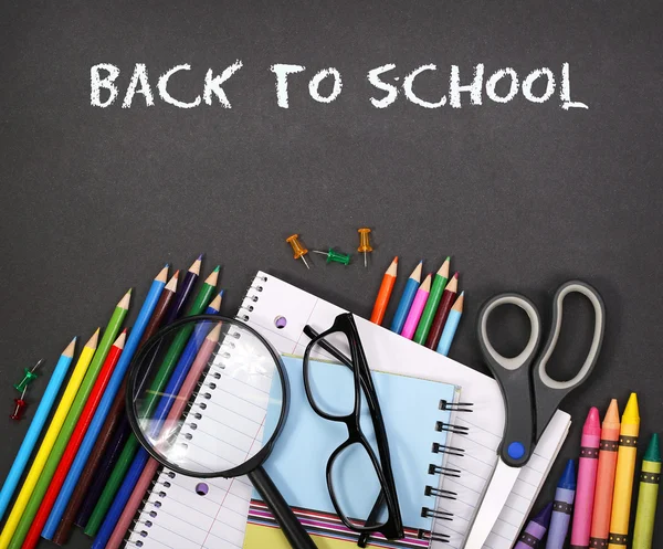 Notebook, exercise book, scissors and pencils on black board bac — Stock Photo, Image