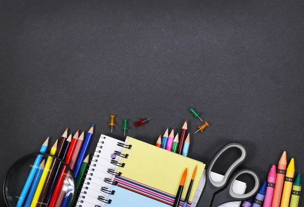 Notebook, exercise book, scissors and pencils on black board bac — Stock Photo, Image