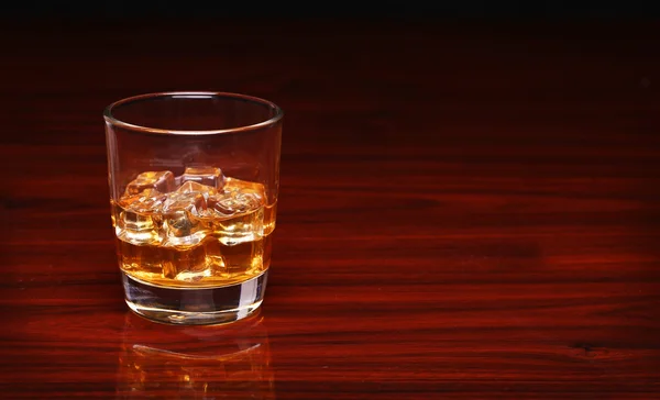 Glas alkohol scotch whisky med isbit på träbord en — Stockfoto