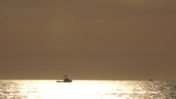 Silhouetted Vissersboot Zee Zeilen Zon Verlichte Wateren Onder Warme Hemel — Stockvideo