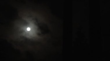 Karanlık gece gökyüzünün geniş açılı görüntüsü dolunaydan geçen bulutlarla..