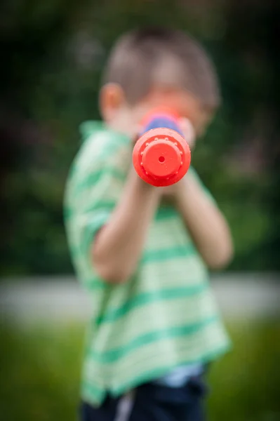 Ung pojke syftar en vatten pistol. — Stockfoto