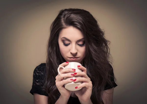 Ung kvinna dricker ur en kopp. — Stockfoto