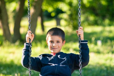 Güneşli bir günde ağaçları ile sallanan genç çocuk