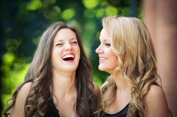 Twee mooie meisjes lachen samen buitenshuis — Stockfoto