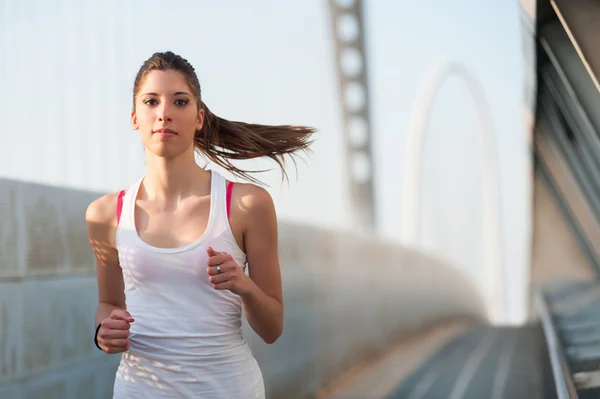 Jonge vrouw rent buiten op een moderne brug. — Stockfoto