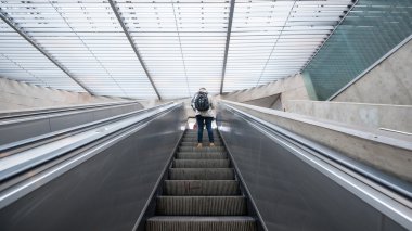 Tourist inside metro station on escalators. clipart