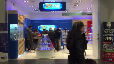 Tim dükkânın önünde yürüyen insanlar.