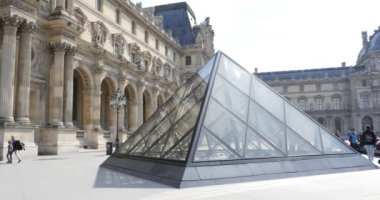 Louvre Müzesi önünde yürüyen insanlar