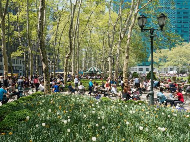Turist ve New Yorklular Bryant Park 'ta öğle yemeğinin tadını çıkarıyorlar