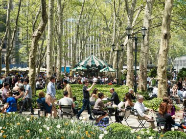Turist ve New Yorklular Bryant Park 'ta öğle yemeğinin tadını çıkarıyorlar