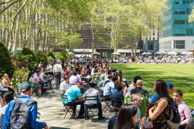 Turist ve New Yorklular Bryant Park 'ta öğle yemeğinin tadını çıkarıyorlar