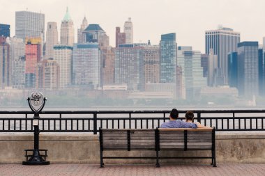 Çift New York'taki Manhattan siluetinin önünde rahatlatıcı