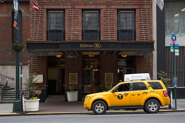 Желтый кэб заканчивается перед отелем Hilton в Нью-Йорке — стоковое фото