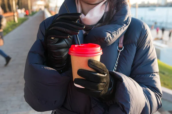 the girl drinks coffee in the cold. A glass of hot drink in nature