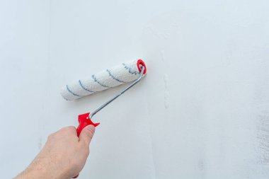 Duvarı hazırlama sürecinde bir inşaat tekeriyle el ele. Odayı yenileme ve dekore etme konsepti. Antiseptik tedavisi. Duvarı boyama ya da duvar kağıtları için hazırlıyorum..