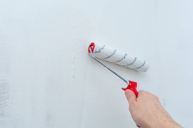 Duvarı hazırlama sürecinde bir inşaat tekeriyle el ele. Odayı yenileme ve dekore etme konsepti. Antiseptik tedavisi. Duvarı boyama ya da duvar kağıtları için hazırlıyorum..