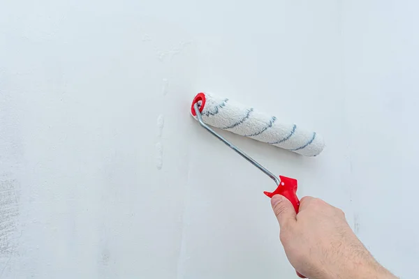 Hand with a construction roller in the process of priming the wall. The concept of renovation and decoration of the room. Antiseptic treatment. Preparing the wall for painting or wallpapering.