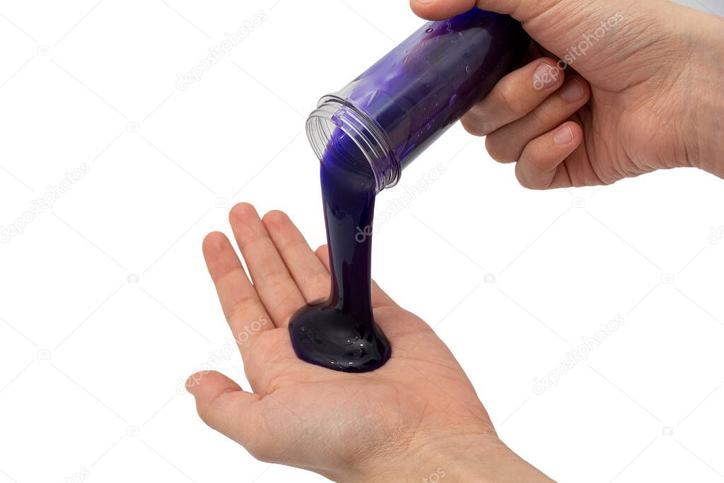 A child's hand pours blue mucus from a transparent bottle into the palm. Game, entertainment concept.