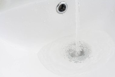 Musluktan lavaboya su akar. Kanalizasyon ve drenaj tıkanıklığı, tesisat tamiri ve önleme kavramı.