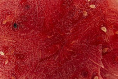 Bir karpuzun içindeki bir dilimin yakın plan çekiminde, siyah tohumlu kırmızı bir yüzey metni kopyalamak için bir yere sahiptir. Arkaplan ve karpuz posası dokusu.