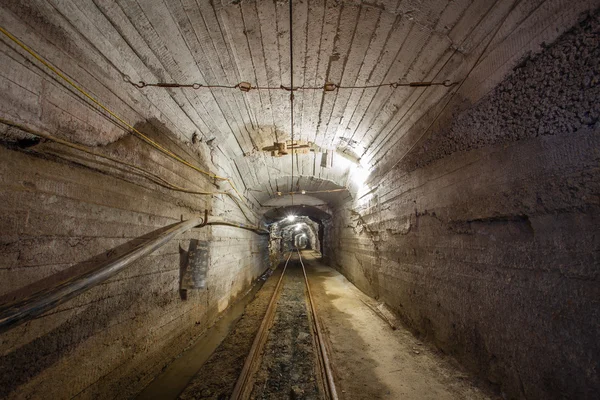 Passagem subterrânea de mina com trilhos e luz — Fotografia de Stock