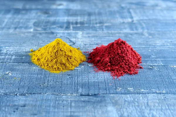 A heap of ground pepper and a heap of ground turmeric on a gray table