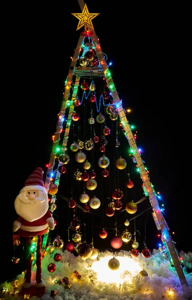 Alternative Christmas tree on a dark black background. Christmas decorations on a construction ladder.