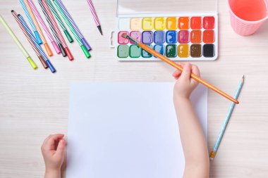 Çocuk, kağıt üzerinde bir fırçayla resim çizer, masada suluboya resimler, çocuklar için yaratıcılık, çocuklarda hayal gücünün gelişimi