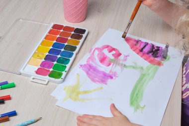 Çocuk, kağıt üzerinde bir fırçayla resim çizer, masada suluboya resimler, çocuklar için yaratıcılık, çocuklarda hayal gücünün gelişimi