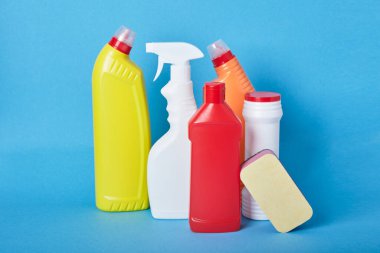 Açık mavi arka plandaki deterjanlar için etiketsiz çeşitli beyaz plastik şişeler. Fotokopi alanı, deterjan şişesi, tuvalet temizleyici ve sprey şişesi.