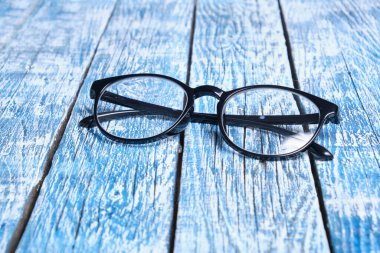 Mavi ahşap arkaplan kopyalama alanı üzerinde siyah çerçeveli gözlük