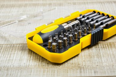 Tornavida ve nozüller plastik bir kutuda, fotokopi yerinde, tornavida başlıkları tahta arka planda