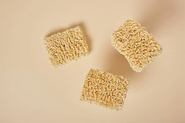 uncooked dried instant noodles on beige background. top view copy space