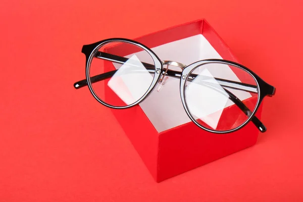 Lunettes en boîte cadeau rouge sur fond rouge — Photo