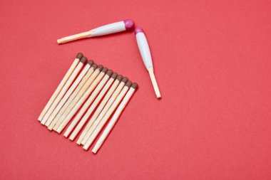 Kırmızı arka planda kibritten yapılmış bir evin silüeti, neme dayanıklı kibritlerden yapılmış bir çatı, sigorta konsepti.