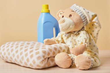 yumuşak ekose ve oyuncak ayı ve bej arka planda jöle ile yıkanan bir şişe