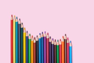 Pembe arkaplandaki renkli kalemler üst görünümde kopya alanı renkli kalemler grafik şeklinde.