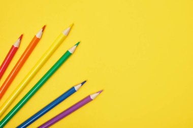Sarı arkaplan fotokopi alanı üst görünümünde birkaç renkli kalem