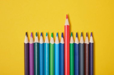 Sarı arka plan görünümünde renkli kalemler. Bir kalem öne çıkıyor.