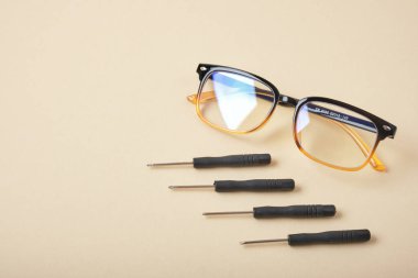 Bej arka plan gözlüklü küçük tornavidalar ve gözlük onarım konsepti fotokopi alanı
