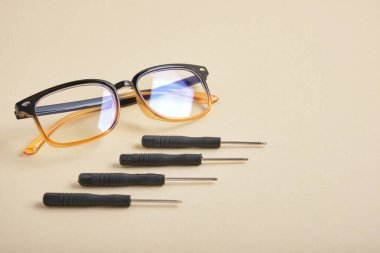 Bej arka plan gözlüklü küçük tornavidalar ve gözlük onarım konsepti fotokopi alanı