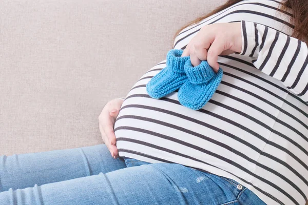 Schwangere Hält Kleine Gestrickte Socken Für Neugeborene Auf Sofa — Stockfoto