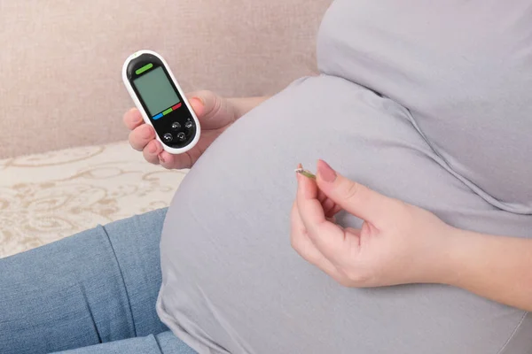 Schwangere Sitzt Auf Der Couch Und Hält Glukometer Und Lanzette — Stockfoto