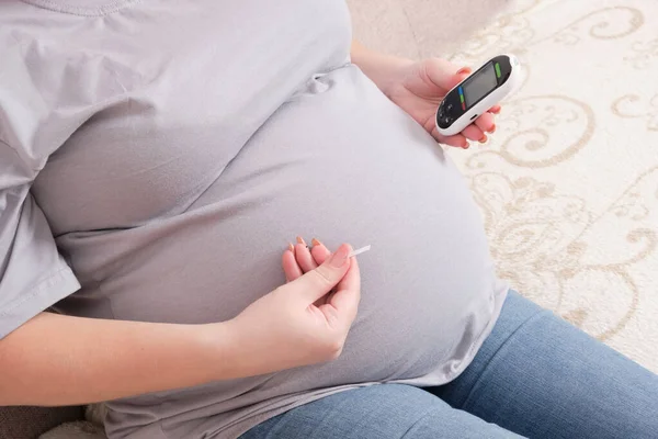 Schwangere Sitzt Auf Der Couch Und Hält Glukometer Und Lanzette — Stockfoto