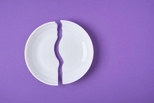 Зламана біла тарілка на фіолетовому фоні копіювання простору — стокове фото