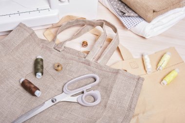 İplik makaraları, makas, dikiş makinesi ve eko keten çanta, ev yapımı alışveriş çantası.